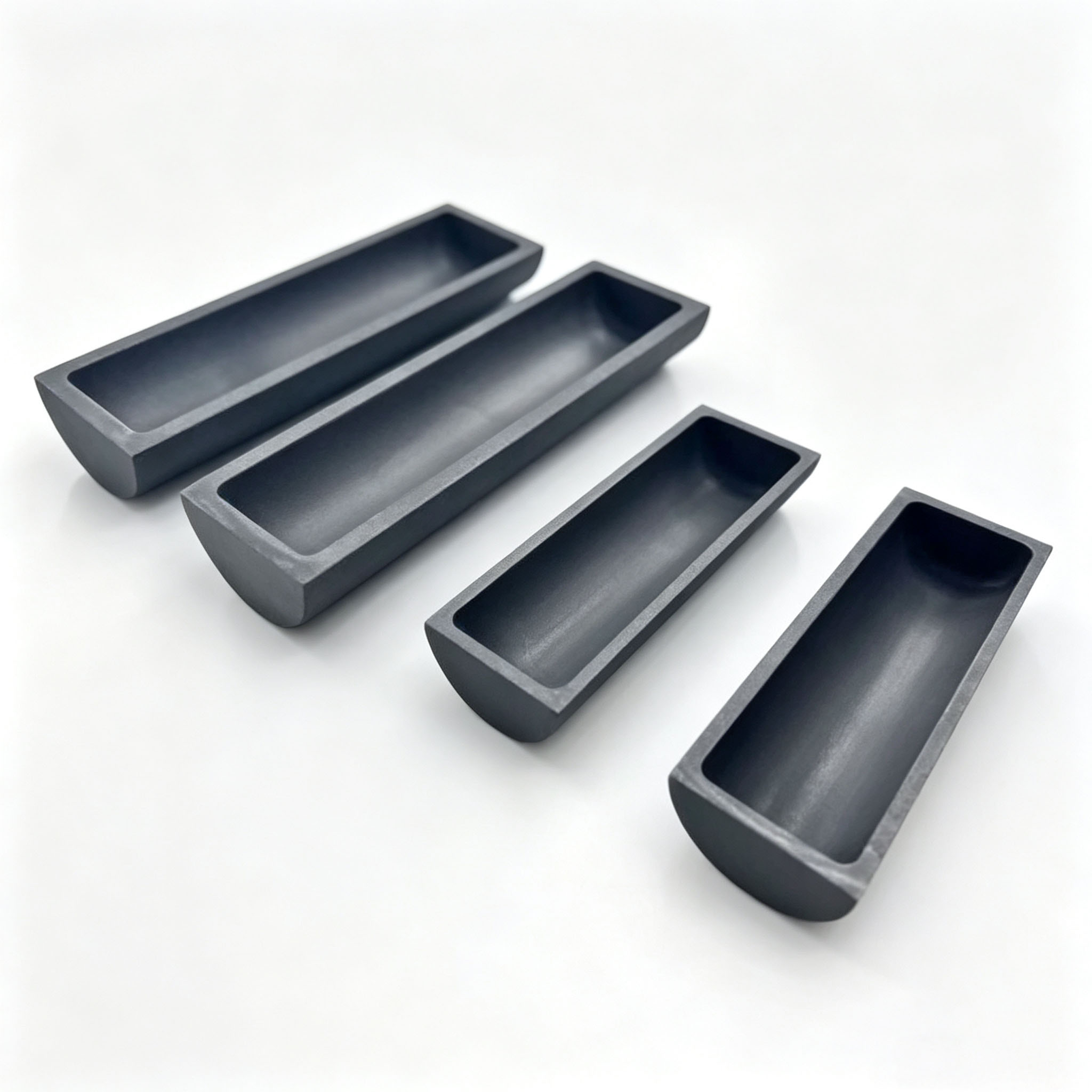 Quatre petits bateaux en graphite de diff&eacute;rentes longueurs, plateau de frittage en graphite poli